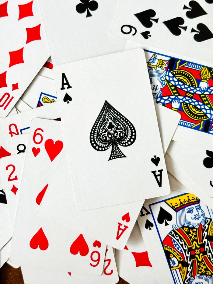 about-us A scattered deck featuring the Ace of Spades and various playing cards.