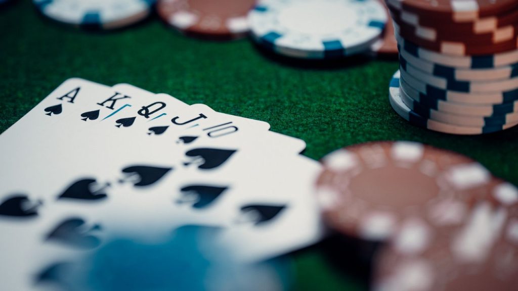 close-up-of-cards-15793559 Close-up of a royal flush poker hand surrounded by colorful chips on a green table.